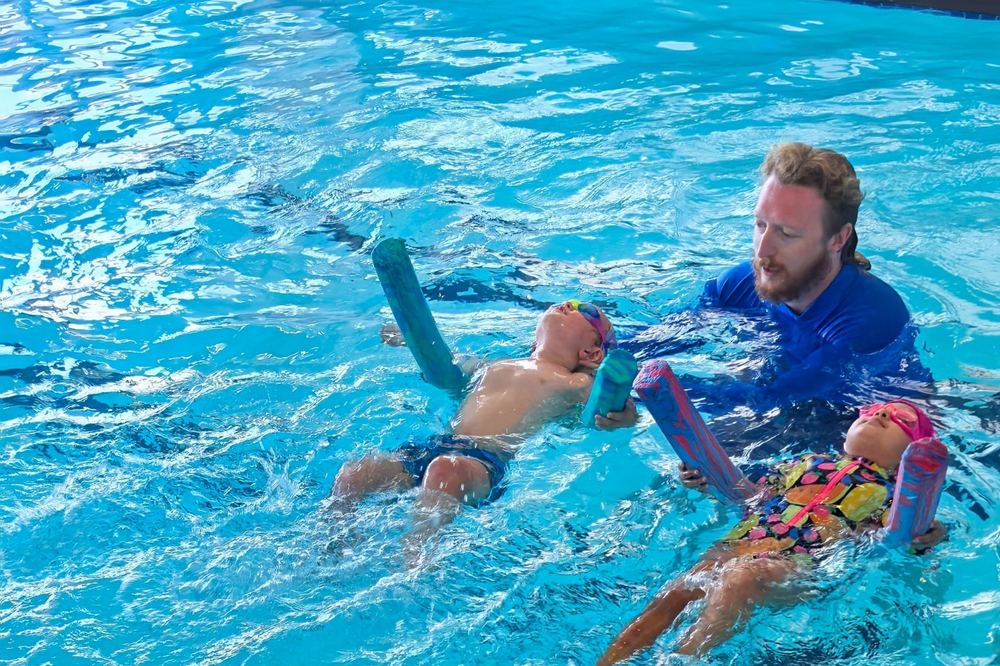 A Swimmable coach working with two young swimmers